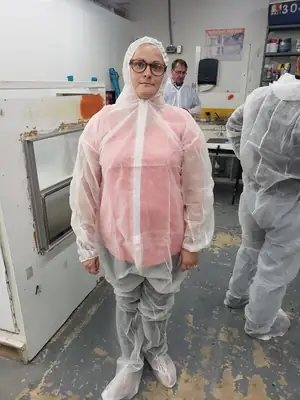 Technician in a protective suit and respirator inside a lab