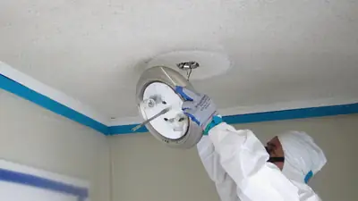 Technician in a protective suit working on a ceiling