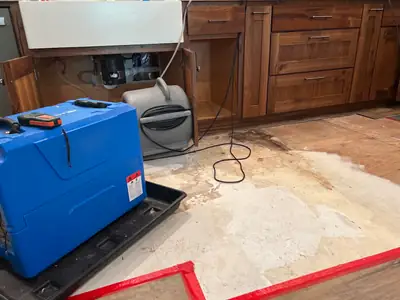Dehumidifier drying a floor beside cabinets