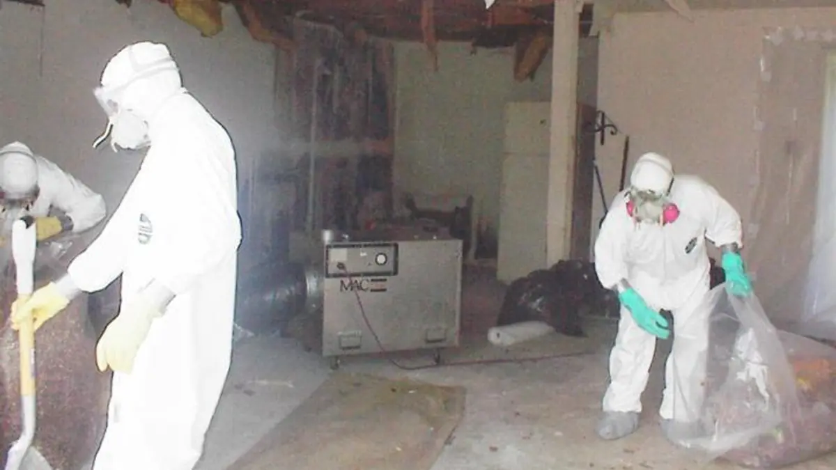 Technicians in protective suits removing ceiling material