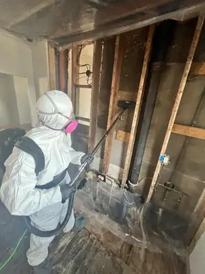 Technician in a protective suit at a stripped wall