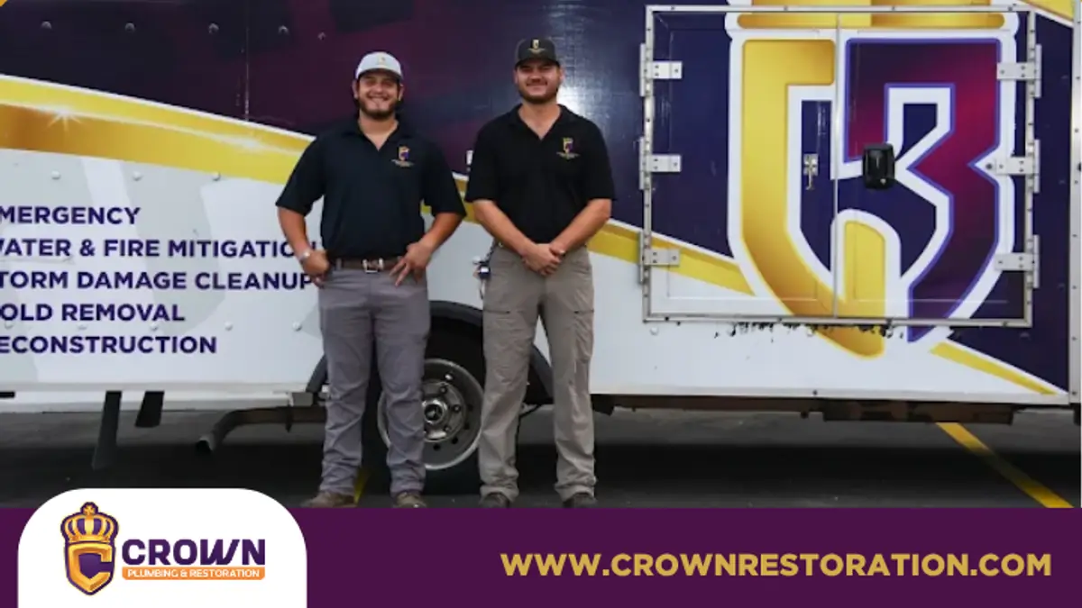 Two Crown Restoration staff in front of a company banner