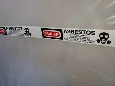 Asbestos warning tape on plastic containment