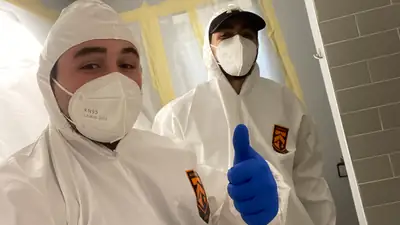 Two technicians in protective suits and masks