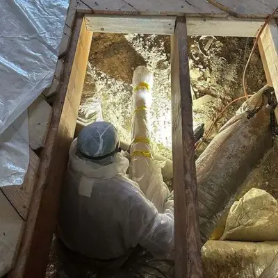 Worker in a protective suit inside an attic