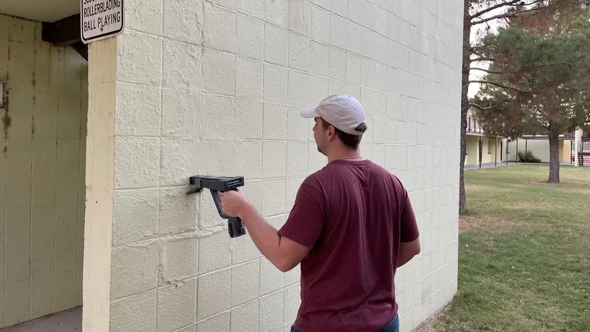 Worker taking a material sample from an exterior wall