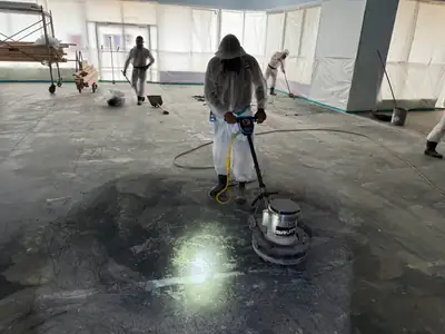 Crew working on a bare concrete floor during abatement