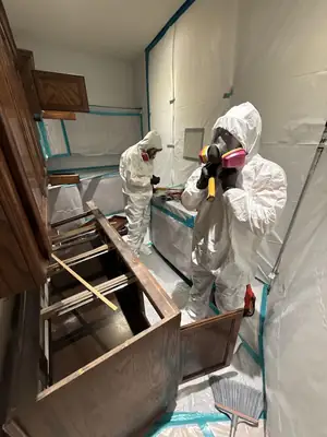 Technician in a protective suit at kitchen cabinets