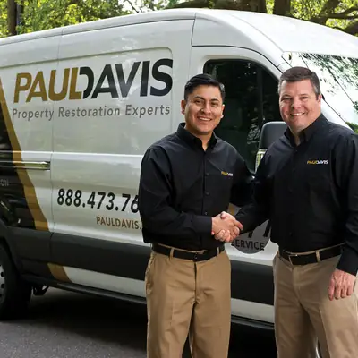 Two Paul Davis staff beside a van