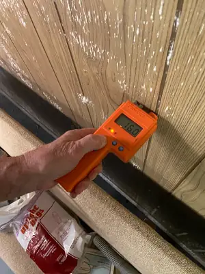Moisture meter held against a window frame