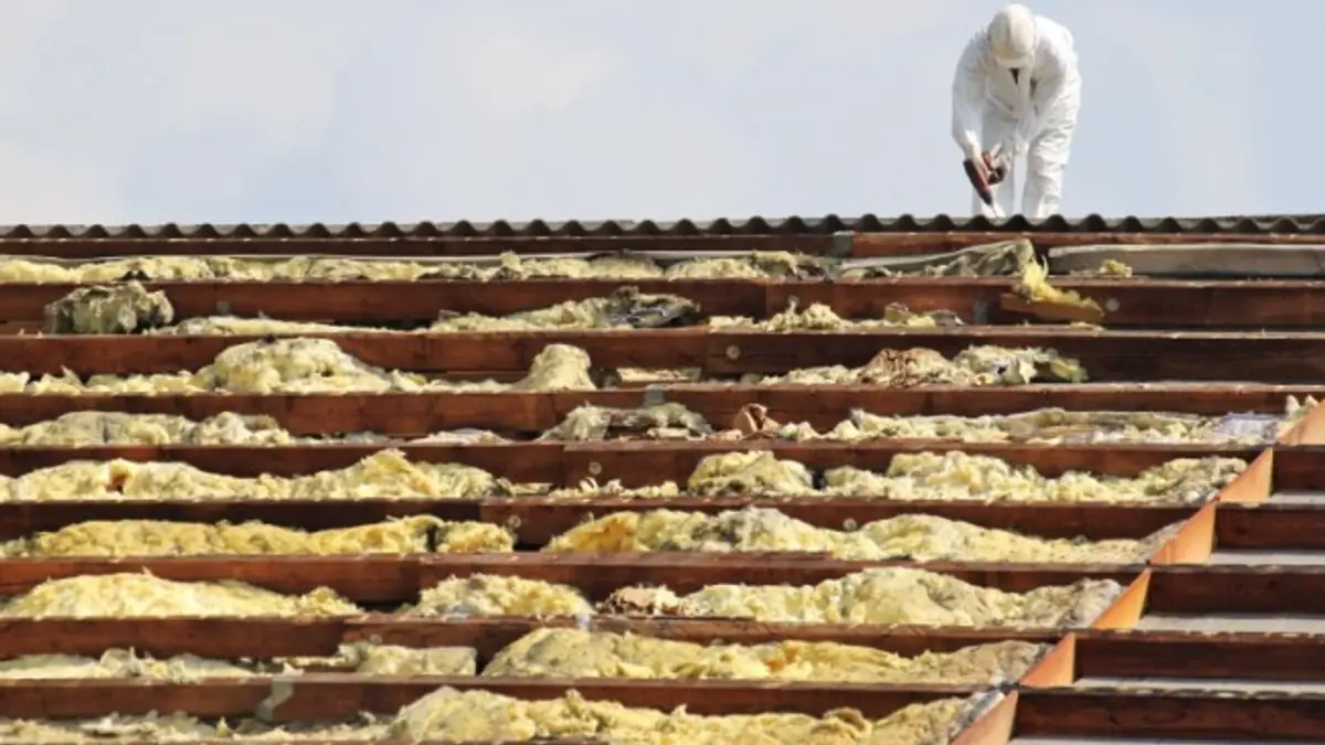 Worker in a protective suit removing roofing material