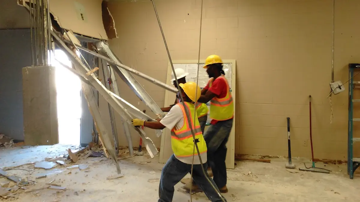 Crew in hard hats demolishing an interior wall