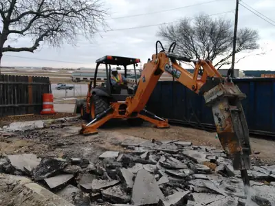Backhoe breaking up concrete