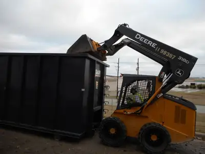 Skid steer loading a dumpster