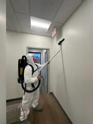 Technician in a protective suit spraying a wall