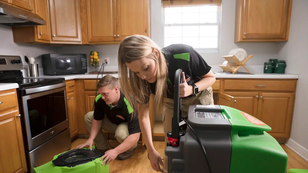 Technician setting up drying equipment in a kitchen