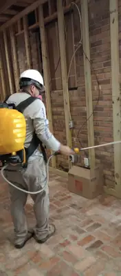 Technician in protective gear spraying a wall